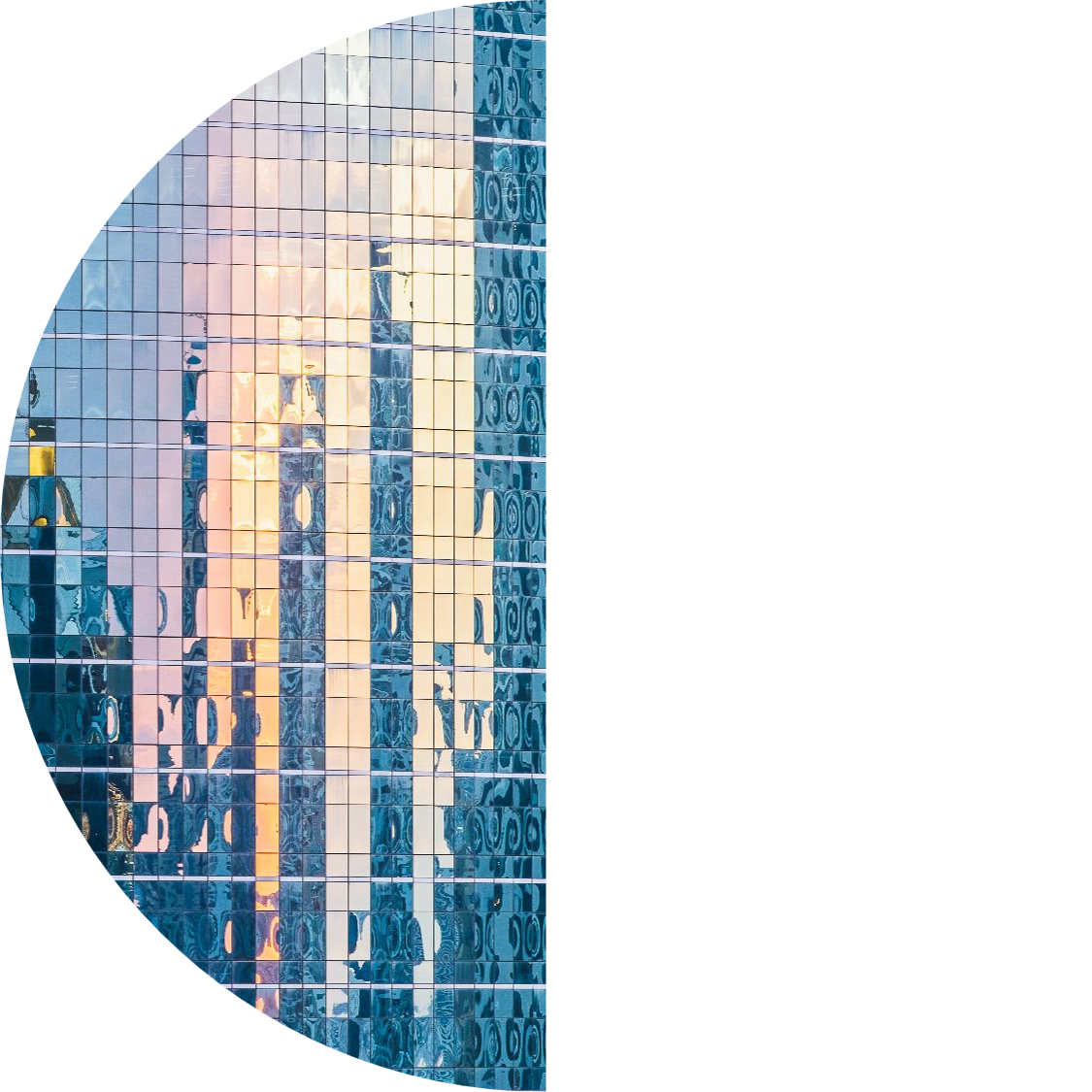 Close-up of a glass office building facade reflecting a warm sunset, with blue-tinted windows forming a grid pattern.