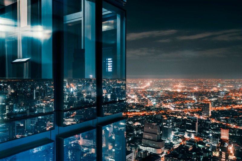 Corner glass window with glowing crowded city Corner glass window with glowing crowded city